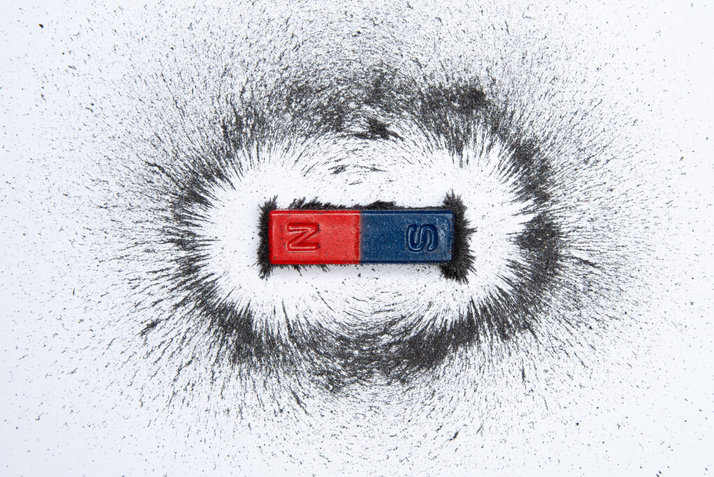 Bar magnet with iron powder magnetic field on white background