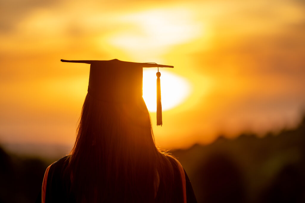 University female graduates Wearing a black robe, wearing a black hat, looking at the sunset