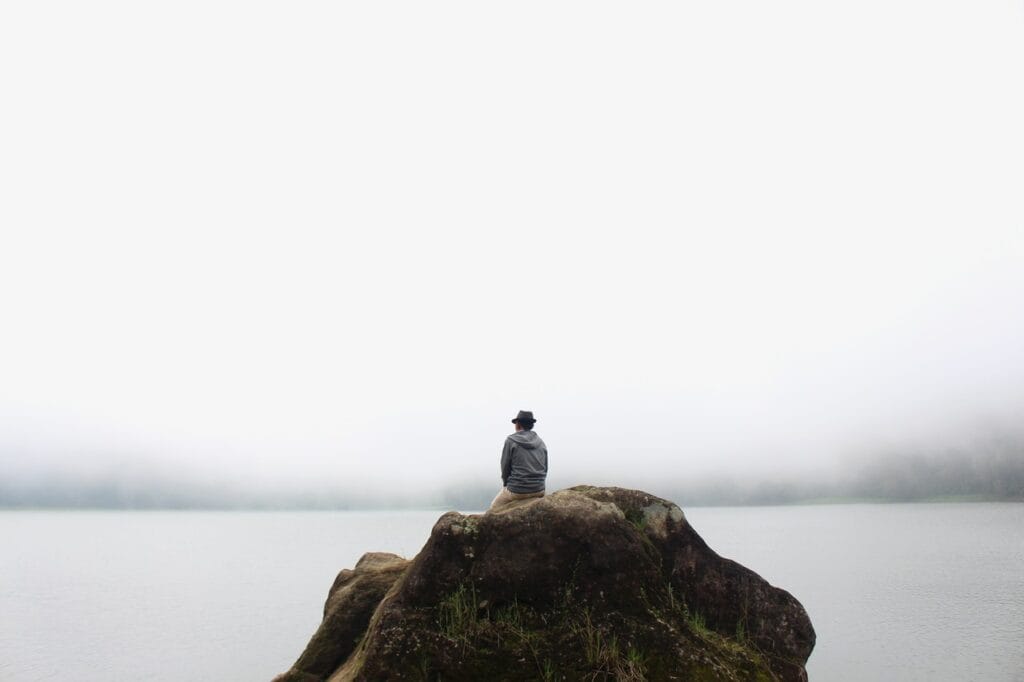 Loneliness - person sitting on a rock by themselves 